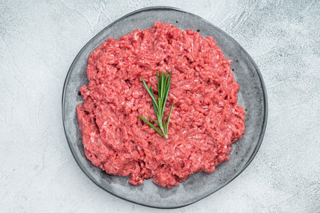 Uncooked raw minced pork and beef meat slab with herbs and pepper on rustic board highlighting raw texture for culinary and food preparation visualsの写真素材