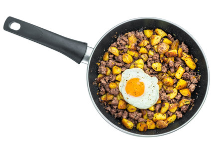 Classic beef hash with fried potatoes and sunny egg in skillet on white background ideal for breakfast, hearty meals and cooking visualsの写真素材