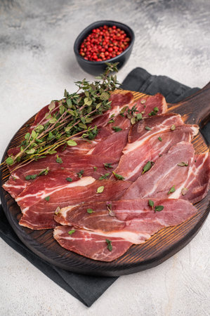 Guanciale dried speck ham, pork cured meat on wooden board. grey background. top view.の写真素材