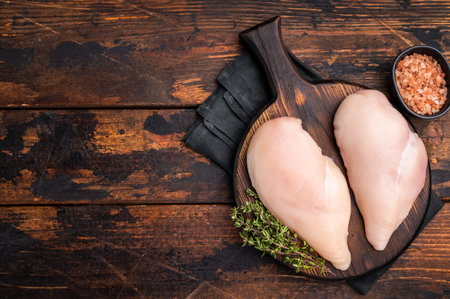 Boneless chicken breasts, neatly arranged on a cutting board. The perfect choice for meal prep or a delicious family dinner. wooden background. top view.の写真素材