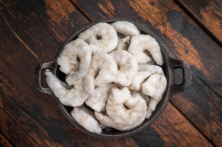 Frozen raw shrimp on a dark rustic wooden background. High-quality seafood ingredient for healthy gourmet cookingの写真素材