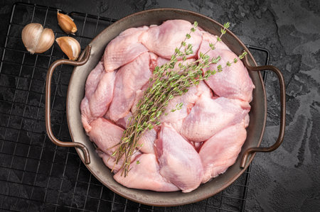 Raw quail breast fillets with thyme and garlic in a metal pan on a dark background. Ready for seasoning and roastingの写真素材