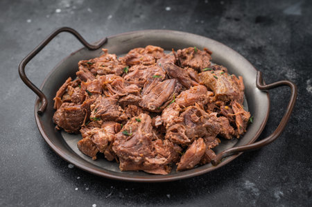 Rustic braised moose venison stew, shredded and savory, plated with fresh rosemary on a metal dish...
