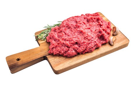 Raw ground venison (deer meat) with fresh rosemary and garlic on a rustic wooden board, ready for a...