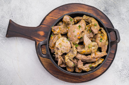 Cooked chicken gizzards with herbs in cast iron pan on white background perfect for rustic food photography and recipe designの写真素材