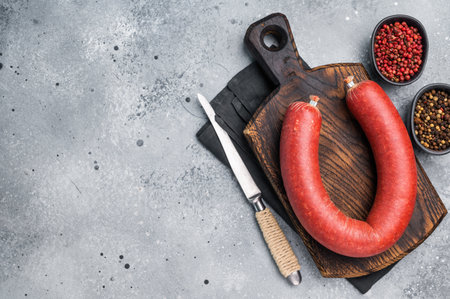 Raw Turkish sucuk (sujuk) on a cutting board with a knife and spices. Traditional spicy dry-cured...
