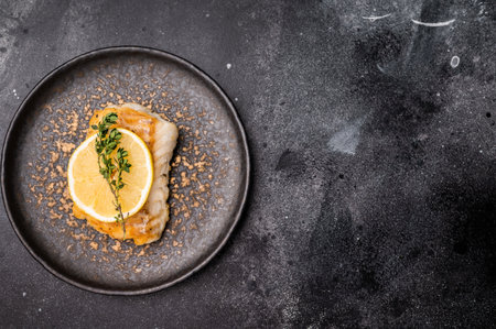 Roast Halibut fish loin fiilet on plate. Black background. top view.