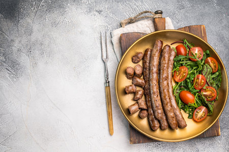 Close up of perfectly charred grilled sausage with salad, ideal for adding flavor to your favorite dishes or sandwiches. white background. top view.の写真素材