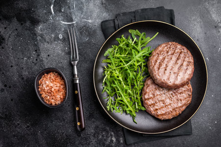 Grilled beef meat patty paired with fresh veggies, an essential component for gourmet burgers. black background. top view.の写真素材