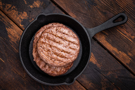 Deliciously charred grilled meat burger patty on the grill, perfect for satisfying cravings at any cookout. wooden background. top view.の写真素材