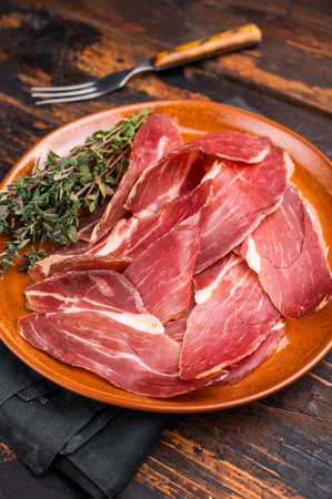 Tyrolean raw ham Speck, Italian sliced cured pork meat. wooden background. top view.