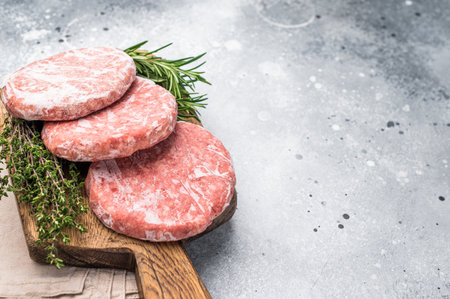 Frozen raw Hamburger beef Patty, uncooked mincemeat. grey background. top view.の写真素材