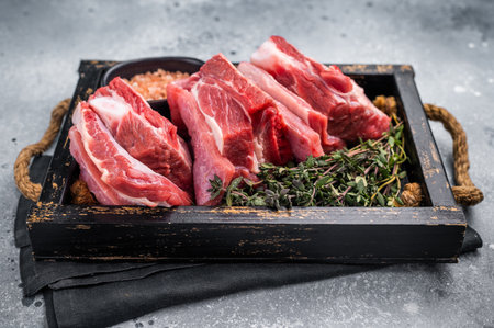 Fresh raw lamb rib cuts, mutton meat with rib bone in wooden board. Grey background. Top view.の写真素材