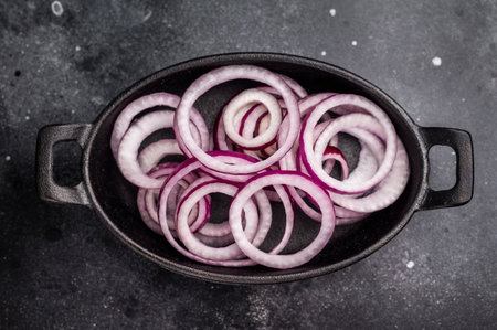 Fresh Raw onion rings in skillet. black background. top view.の写真素材