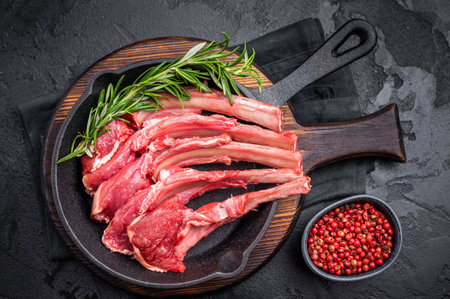 Ready for cooking Raw lamb meat chops, fresh mutton cutlets in a pan. black background. top view.