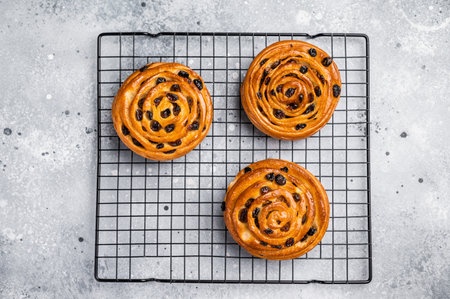Baked Danish pastry, raisin bun on steel rack. grey background. top view.