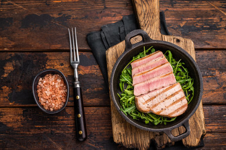 Tender grilled tuna steak on a bed of greens, an exquisite blend of flavors that delights the palate. wooden background. top view.の写真素材
