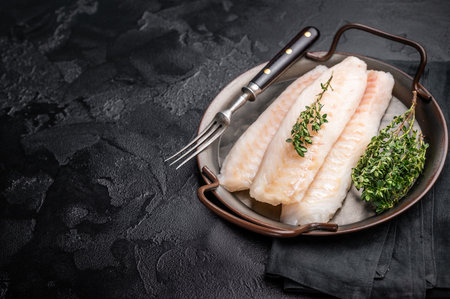 Raw Loin cod fish fillets ready for cooking whitefish in stell tray. black background. top view.