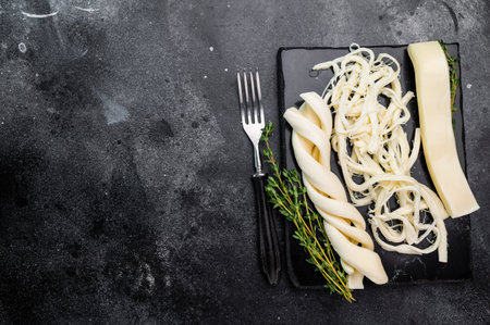 Assortiment of Traditional Caucasian Chechil white cheese on black board, top view