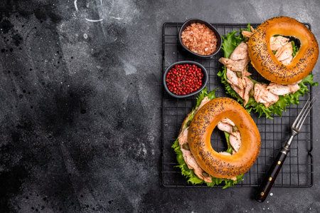 Bagel sandwich with lox, smoked salmon, lettuce and cream cheese on a rack. black background. top view.の写真素材