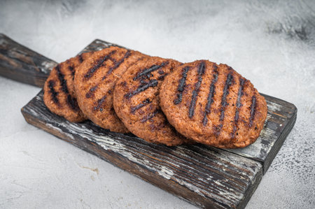 Vegan meatless burger patties grilled and ready to eat plant based protein bbq food on light textured backgroundの写真素材