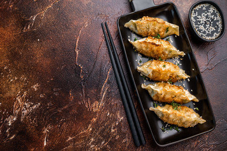 Fried Jiaozi on plate with sauce, Chinese Dumplings with shrimps and vegetables. brown background. top view.の写真素材