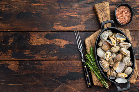 Steamed vongole mollusks in black cast iron skillet. Mediterranean seafood composition with shells, rosemary and salt.の写真素材