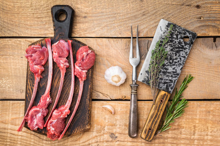Uncooked lamb cutlets on bone with thyme and vintage fork wooden background butcher style copy spaceの写真素材