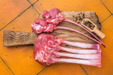 Premium raw lamb rack and sliced chop steaks on wooden board warm terracotta tiles top view culinary ingredientの写真素材