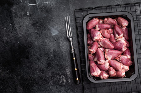 Uncooked poultry hearts in container, dark backdrop accentuates rich pink hue.の写真素材
