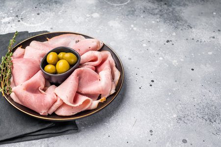Meat appetizer with Sliced Prosciutto Cotto ham and green olives. grey background. top view.の写真素材