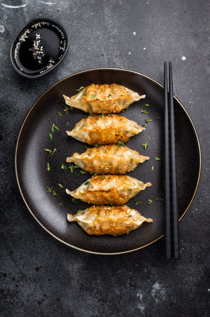 Asian Fried Dumplings, Jiaozi, Gyoza, Dim sum with meat and vegetables on plate. black background. top view.