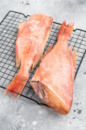 Cut ocean red perch fish on metal rack with thyme. Raw marine seafood ingredient ready for cooking