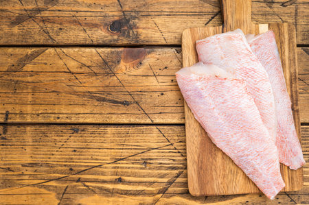 Raw redfish fillets on wooden cutting board. Fresh seafood ingredient on rustic wooden background...