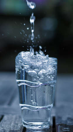 fress drops of water falling in a drinking glassの写真素材