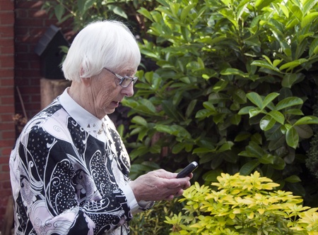 grandmother with mobile phone making a sms