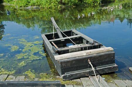 old wooden boat with a rope to pull to the other sideの写真素材