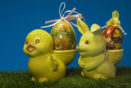 yellow easter duck and bunne in green grass with blue backgroundの写真素材