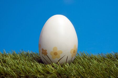 easter egg in grass with blue backgroundの写真素材