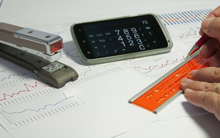 man making diagrams and graphics on  a table with calculator and staplerの写真素材