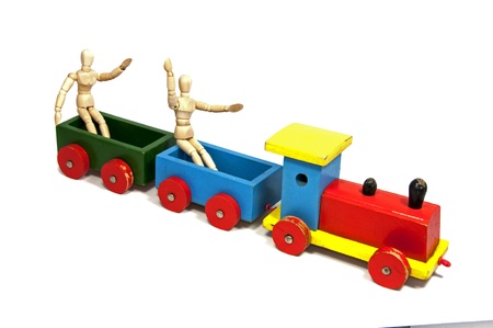 two wooden dolls sitting on a red yellow and green trainの写真素材