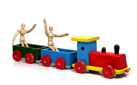 two wooden dolls sitting on a red yellow and green trainの写真素材