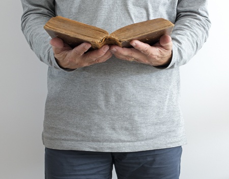 man reading old bible while standing