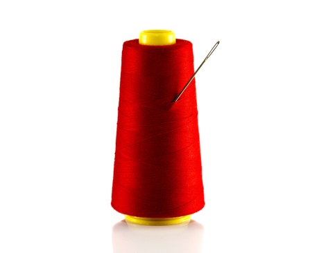 red bobbin with thread and needle isolated on whiteの写真素材