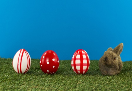 easter eggs and bunny on green grass with blue backgroundの写真素材