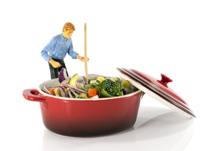 plastic model man stir vegetarian food in red saucepanの写真素材