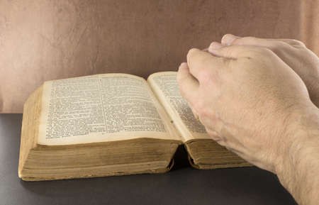 praying hand with old bible book with brown backgroundの写真素材