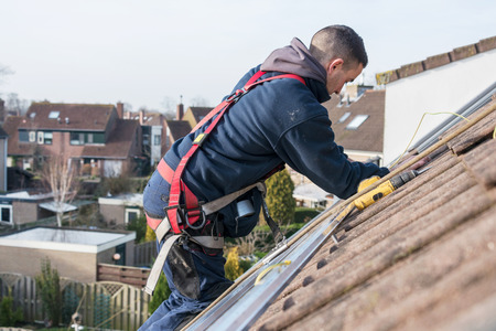 man making the construction for the solar panels high on the roof