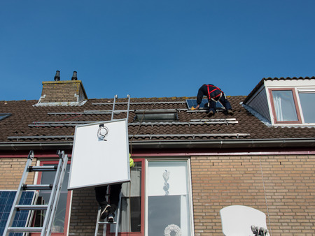 man putting the solar panel to the metal construction on the roofの写真素材