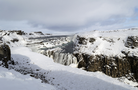 frozen waterfall and mountains in the winter on island icelandの写真素材